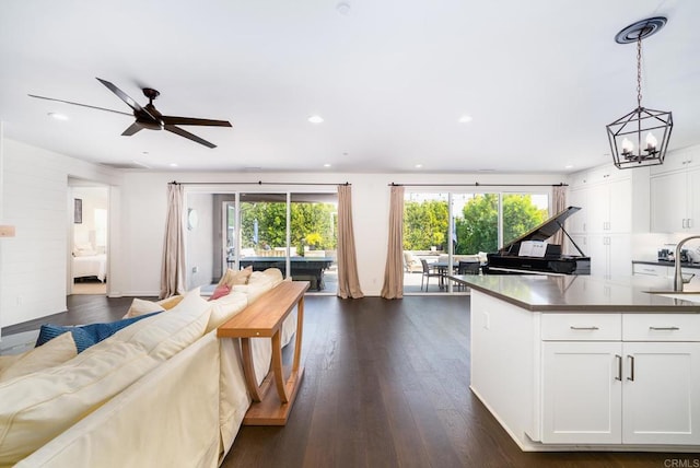 kitchen featuring a sink, dark countertops, dark wood-style floors, open floor plan, and white cabinets