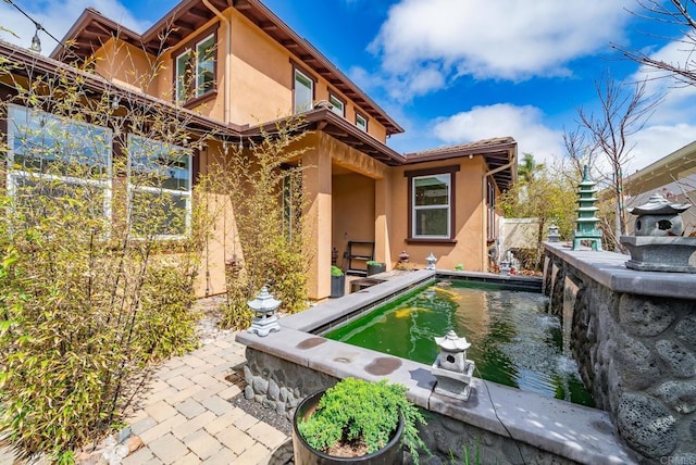 exterior space with stucco siding, a patio, and fence