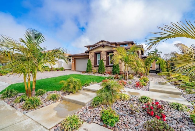 view of front facade with a front yard, driveway, an attached garage, stucco siding, and stone siding