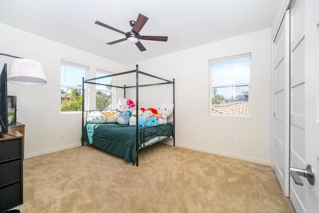 bedroom with light colored carpet, baseboards, and ceiling fan