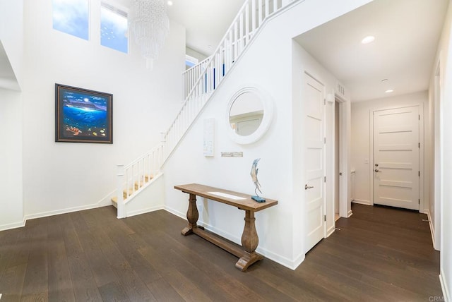 corridor with dark wood-type flooring, baseboards, stairway, recessed lighting, and a notable chandelier