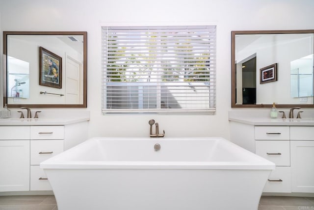 full bathroom with a sink, a soaking tub, two vanities, and tile patterned floors