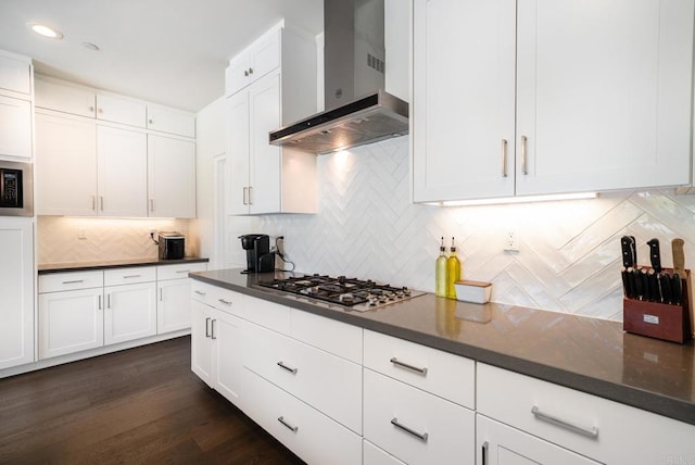 kitchen with decorative backsplash, white cabinets, wall chimney exhaust hood, and stainless steel gas stovetop