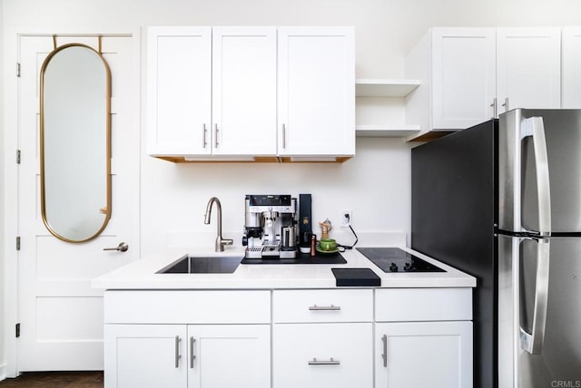 kitchen with a sink, open shelves, white cabinets, and freestanding refrigerator