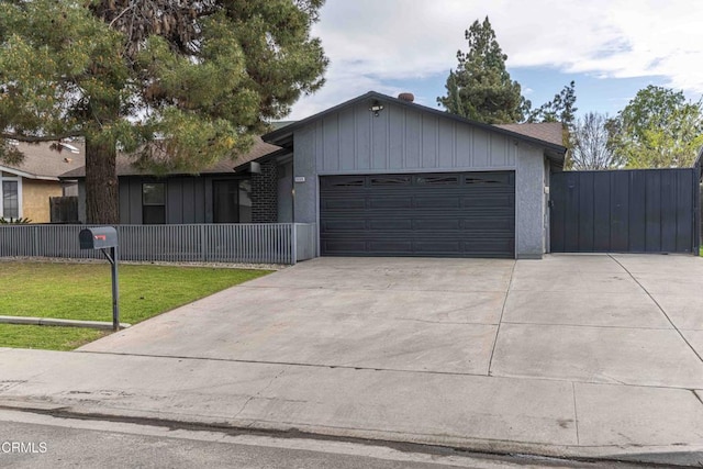 single story home with fence, board and batten siding, concrete driveway, a front yard, and a garage