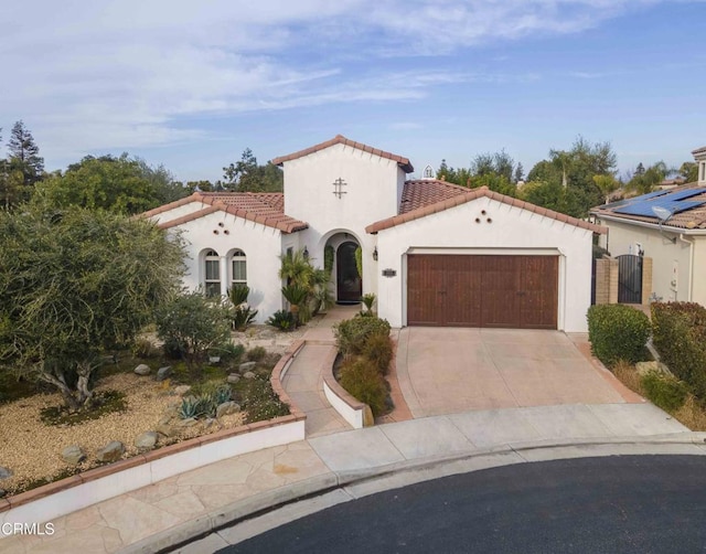 mediterranean / spanish house with stucco siding, concrete driveway, a tile roof, and a garage