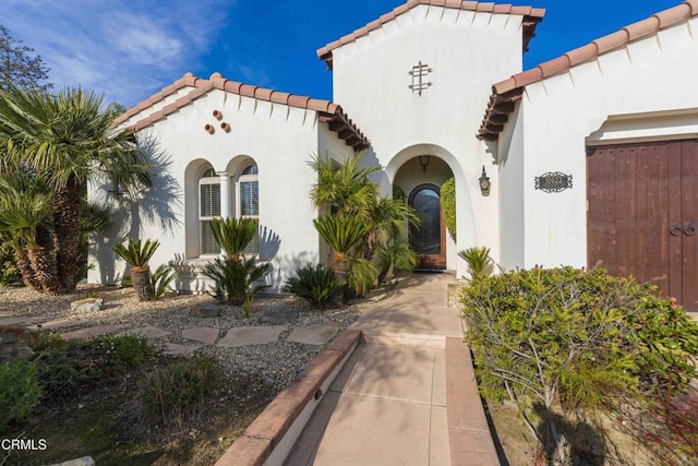 doorway to property with a tiled roof and stucco siding