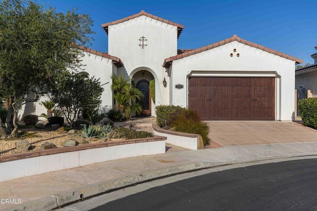 mediterranean / spanish house featuring concrete driveway, an attached garage, and stucco siding