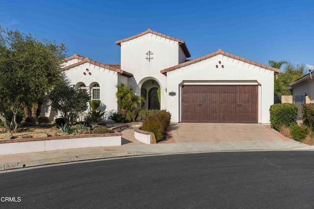 mediterranean / spanish-style home with stucco siding, concrete driveway, an attached garage, and a tile roof