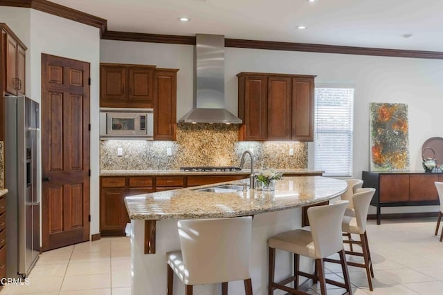 kitchen with backsplash, stainless steel appliances, a kitchen bar, and wall chimney range hood