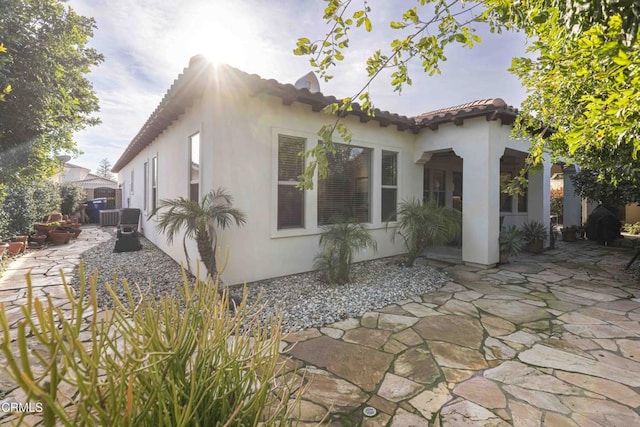 exterior space with stucco siding, a patio, and a tile roof