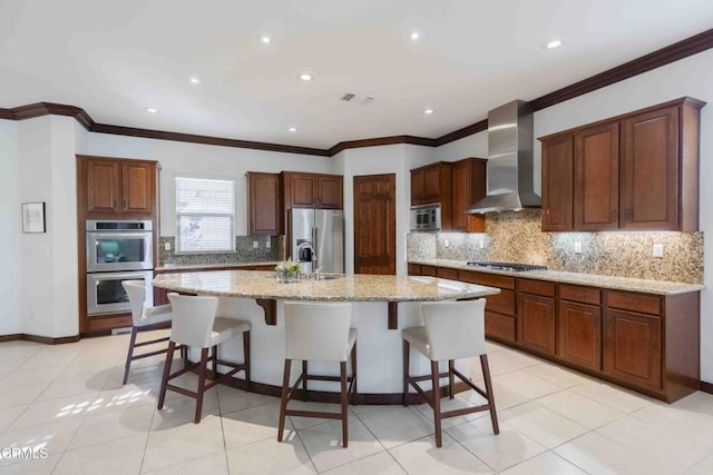 kitchen with a kitchen bar, wall chimney range hood, light tile patterned floors, and stainless steel appliances