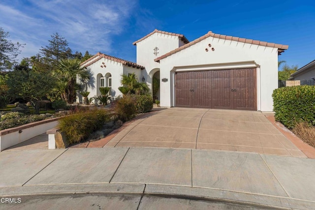 mediterranean / spanish-style house featuring a tile roof, stucco siding, concrete driveway, and a garage