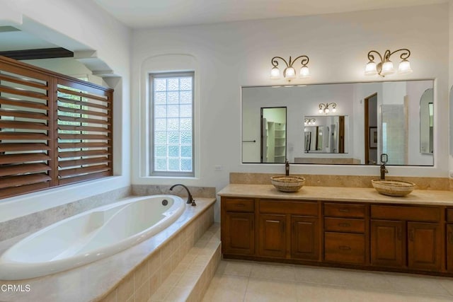 bathroom featuring tile patterned flooring, double vanity, a bath, and a sink