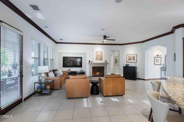 living area with light tile patterned floors, visible vents, arched walkways, and baseboards