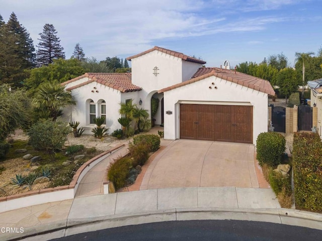 mediterranean / spanish-style home with a tile roof, a garage, driveway, and stucco siding