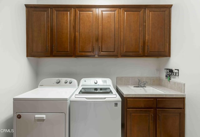 clothes washing area featuring a sink, cabinet space, and washing machine and dryer