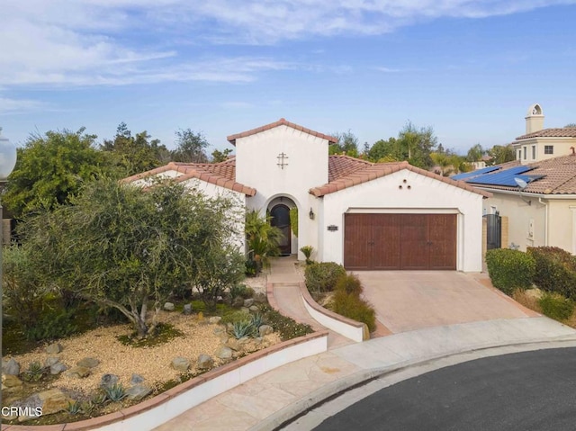 mediterranean / spanish house with stucco siding, driveway, a tile roof, and a garage