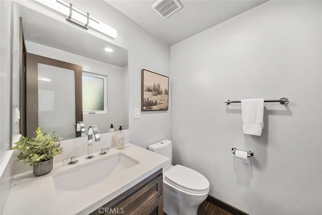 bathroom featuring vanity, toilet, wood finished floors, and visible vents