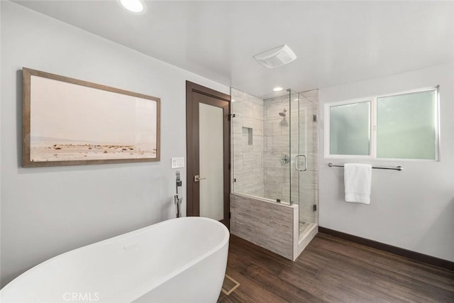 bathroom with a freestanding tub, wood finished floors, recessed lighting, a shower stall, and baseboards