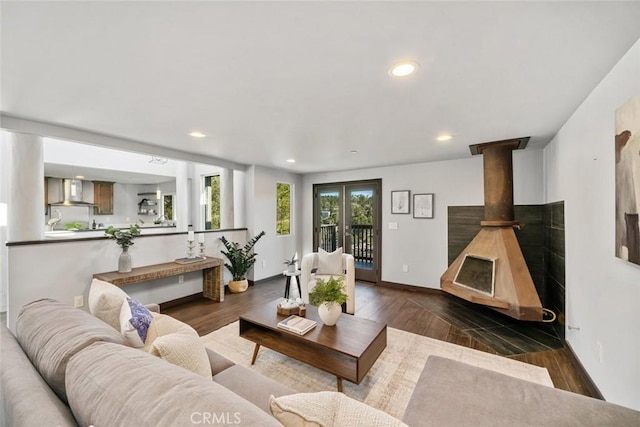 living room featuring recessed lighting, baseboards, wood finished floors, and a wood stove