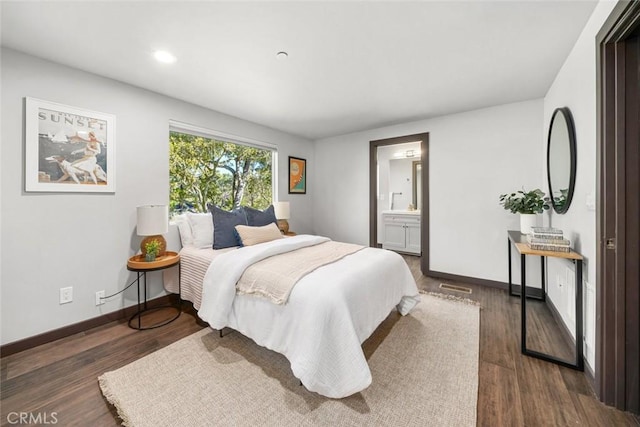 bedroom with visible vents, baseboards, wood finished floors, and ensuite bathroom