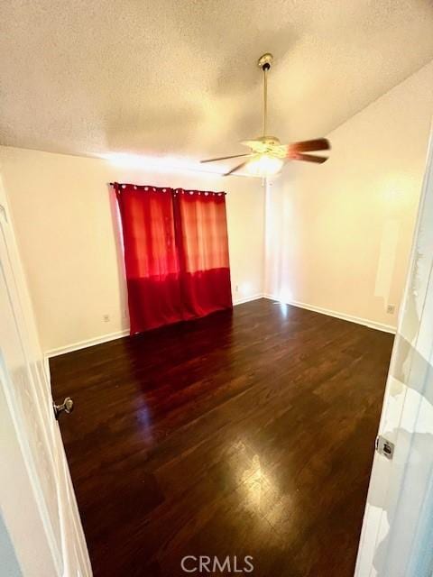 empty room featuring baseboards, a ceiling fan, a textured ceiling, and wood finished floors
