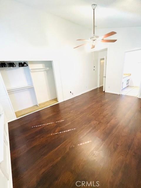 empty room with baseboards, lofted ceiling, a ceiling fan, and wood finished floors