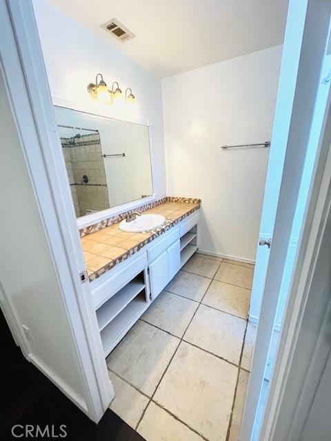 full bathroom with tile patterned floors, visible vents, vanity, and tiled shower