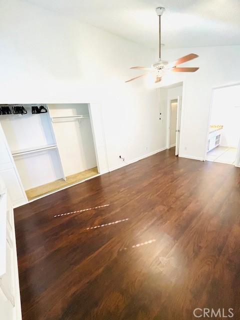 spare room featuring baseboards, lofted ceiling, wood finished floors, and a ceiling fan