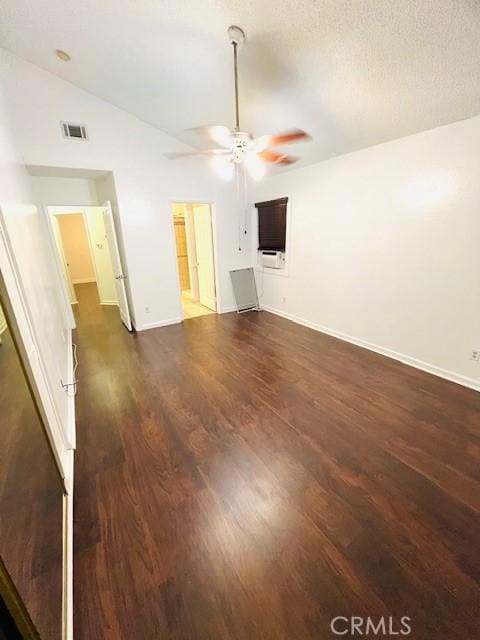 spare room featuring dark wood-style flooring, a ceiling fan, baseboards, vaulted ceiling, and visible vents