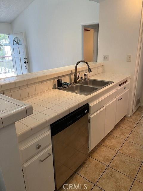 kitchen with tile counters, dishwasher, light tile patterned flooring, white cabinetry, and a sink