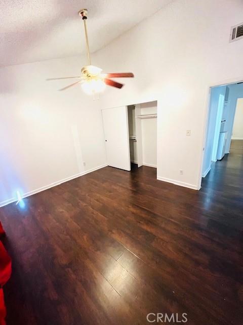 interior space with visible vents, high vaulted ceiling, a ceiling fan, wood finished floors, and baseboards