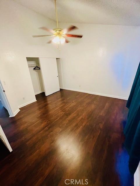 unfurnished bedroom with a closet, a textured ceiling, baseboards, and wood finished floors