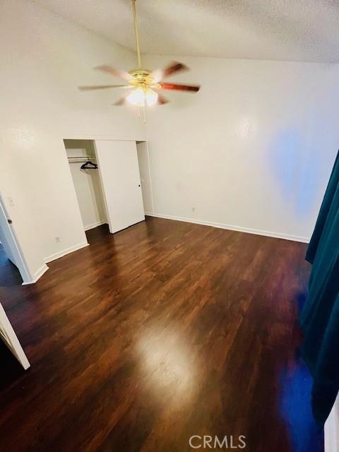 unfurnished bedroom featuring a textured ceiling, baseboards, a closet, and wood finished floors