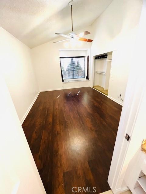 unfurnished room with ceiling fan, baseboards, lofted ceiling, and wood finished floors