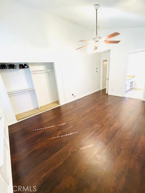 spare room with vaulted ceiling, wood finished floors, baseboards, and ceiling fan