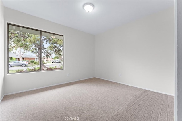 carpeted empty room featuring baseboards