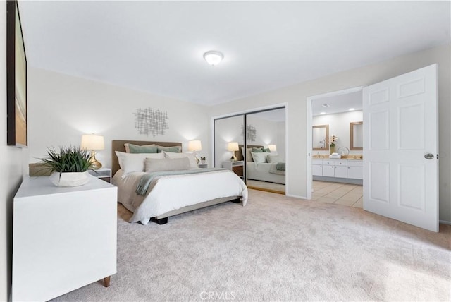 bedroom with a closet, light colored carpet, and ensuite bath