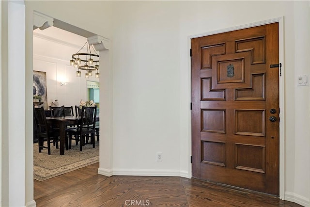 foyer entrance with an inviting chandelier, baseboards, and dark wood-type flooring