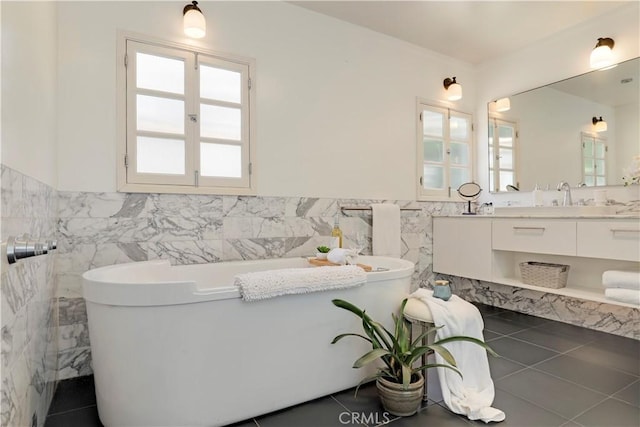 full bathroom featuring tile patterned flooring, vanity, wainscoting, a soaking tub, and tile walls