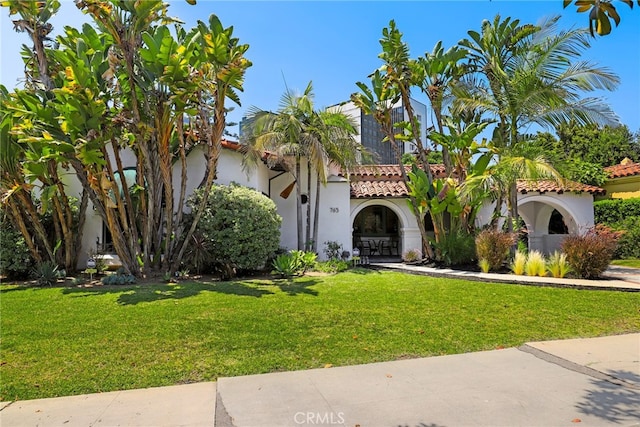 mediterranean / spanish home featuring stucco siding, a front lawn, and a tile roof