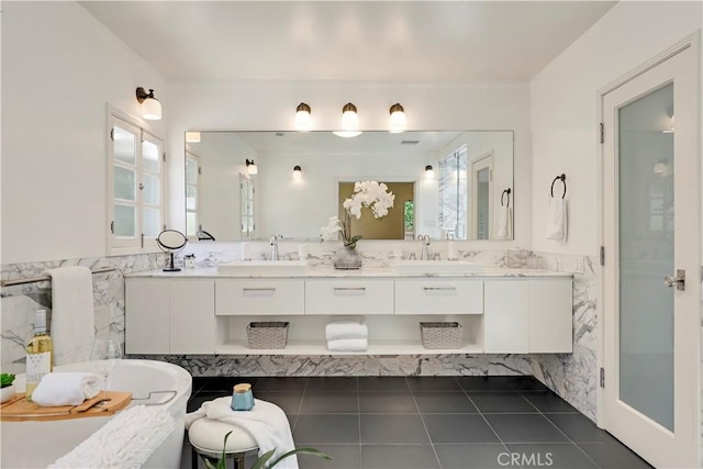 bathroom featuring a freestanding bath, tile walls, and a sink