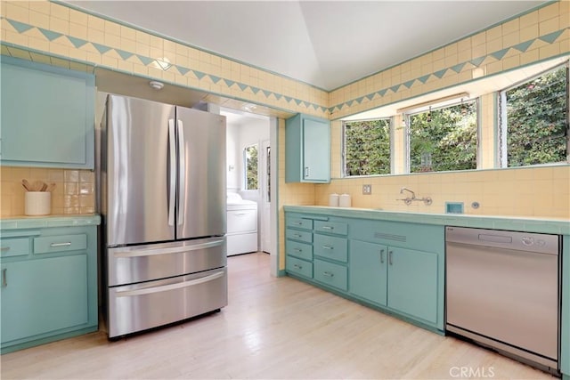 kitchen with lofted ceiling, dishwashing machine, light wood-style flooring, decorative backsplash, and freestanding refrigerator