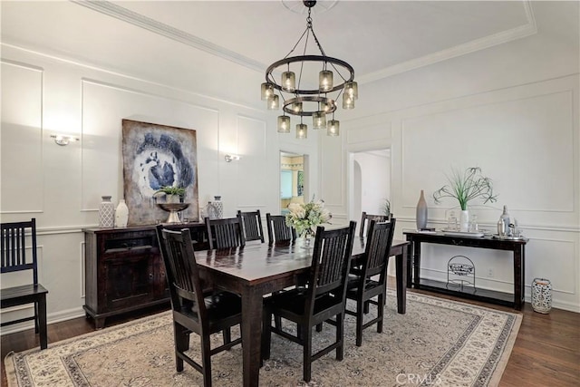 dining space featuring wood finished floors, arched walkways, ornamental molding, a decorative wall, and a chandelier