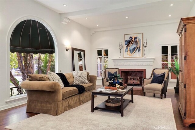 living room featuring a brick fireplace, plenty of natural light, wood finished floors, and recessed lighting