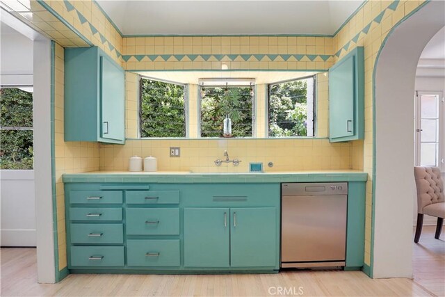 kitchen featuring a sink, backsplash, dishwasher, and tile counters