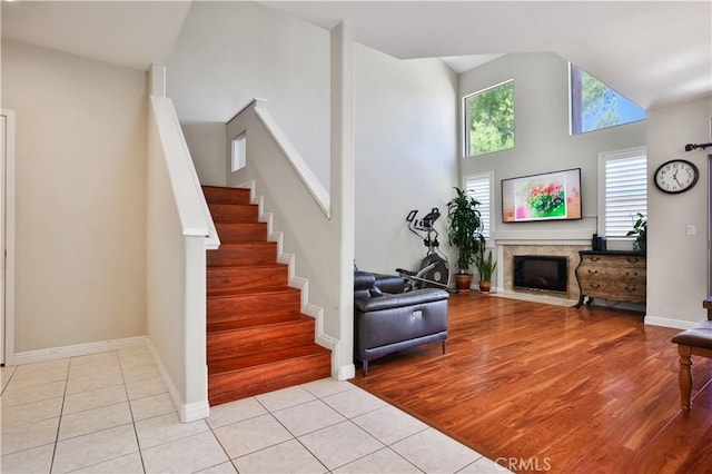 living area featuring stairway, light tile patterned floors, a fireplace, and baseboards