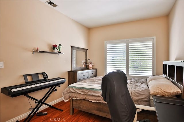 bedroom with visible vents, baseboards, and wood finished floors