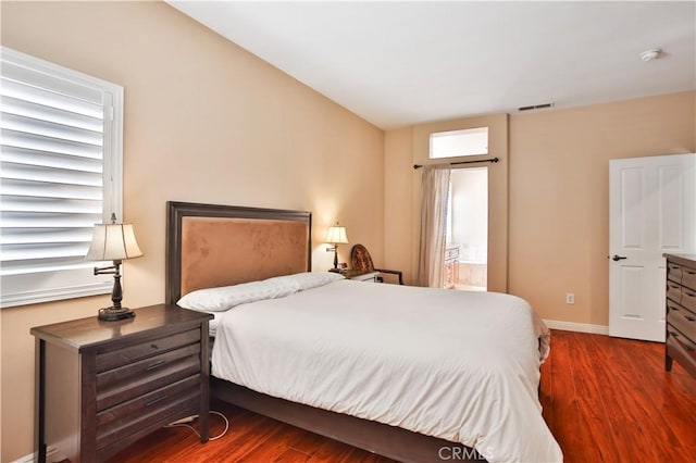 bedroom with visible vents, baseboards, ensuite bath, and wood finished floors